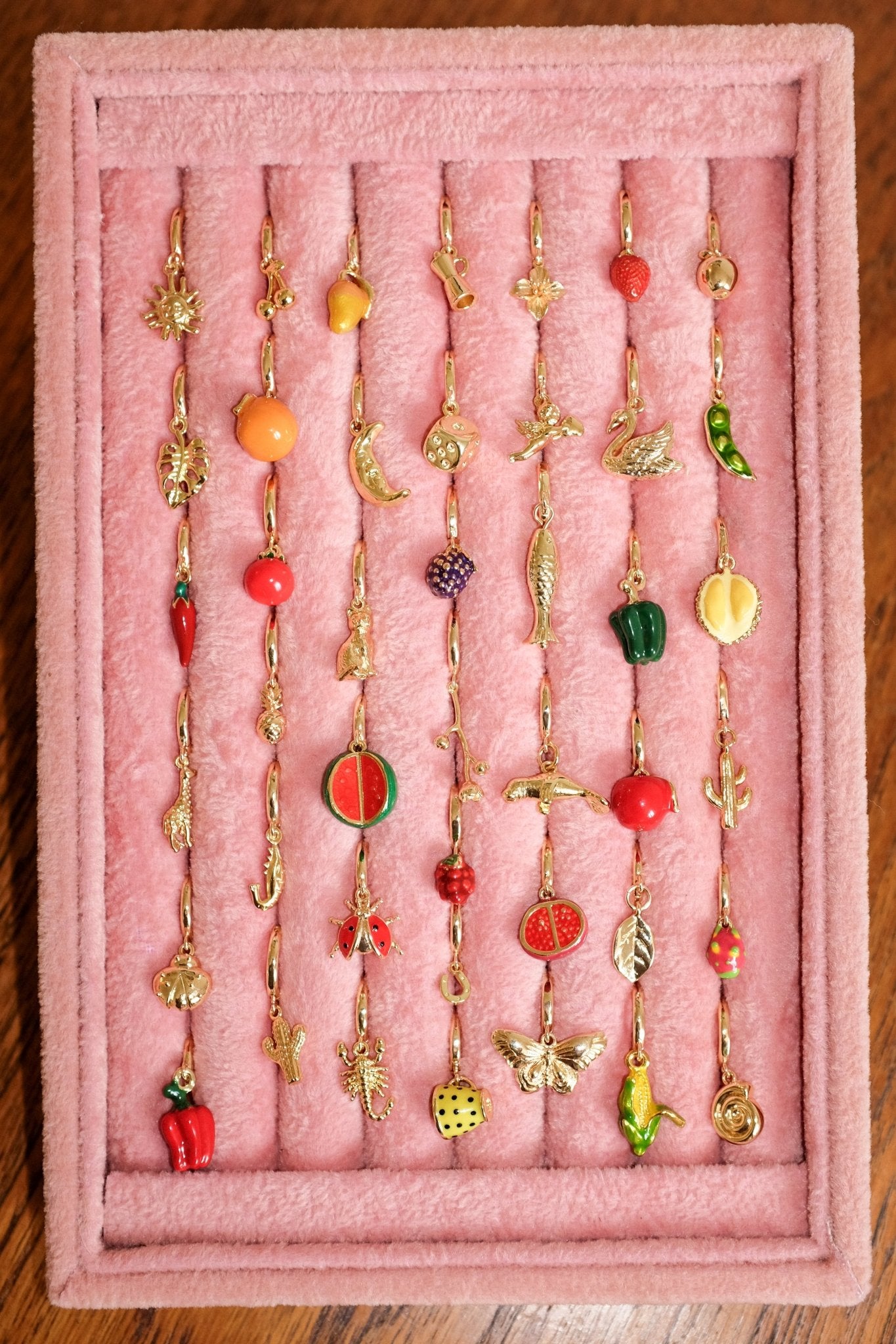 Collection of colorful earrings on a pink display stand.