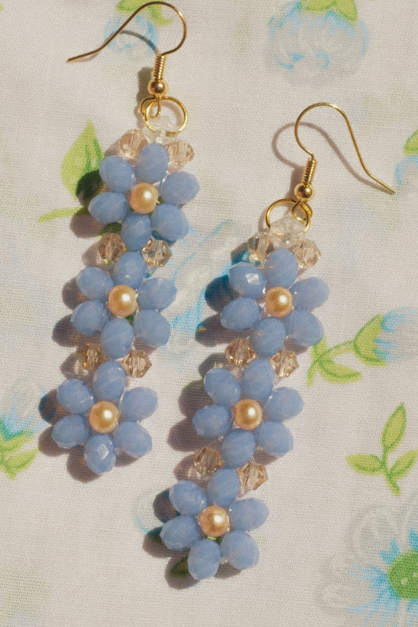 Handmade blue beaded flower earrings displayed against neutral background.