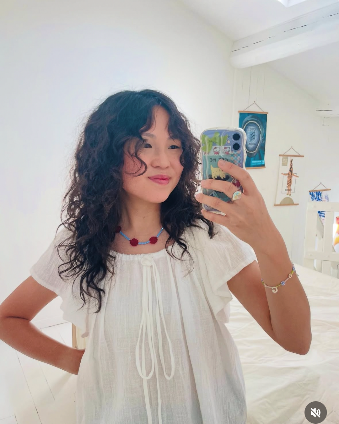 Person taking a mirror selfie wearing a white dress in a bedroom.