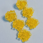 Yellow flower-shaped earrings on a light blue background