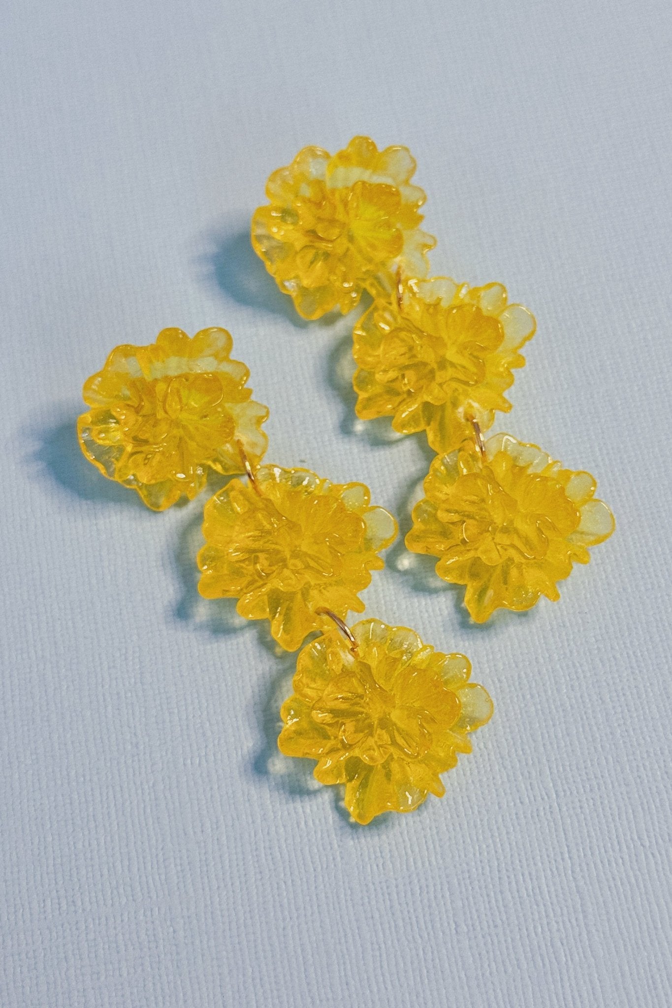 Yellow flower-shaped earrings on a light blue background