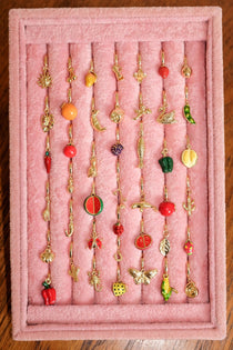 Collection of colorful earrings on a pink display stand.