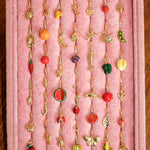 Collection of colorful earrings on a pink display stand.