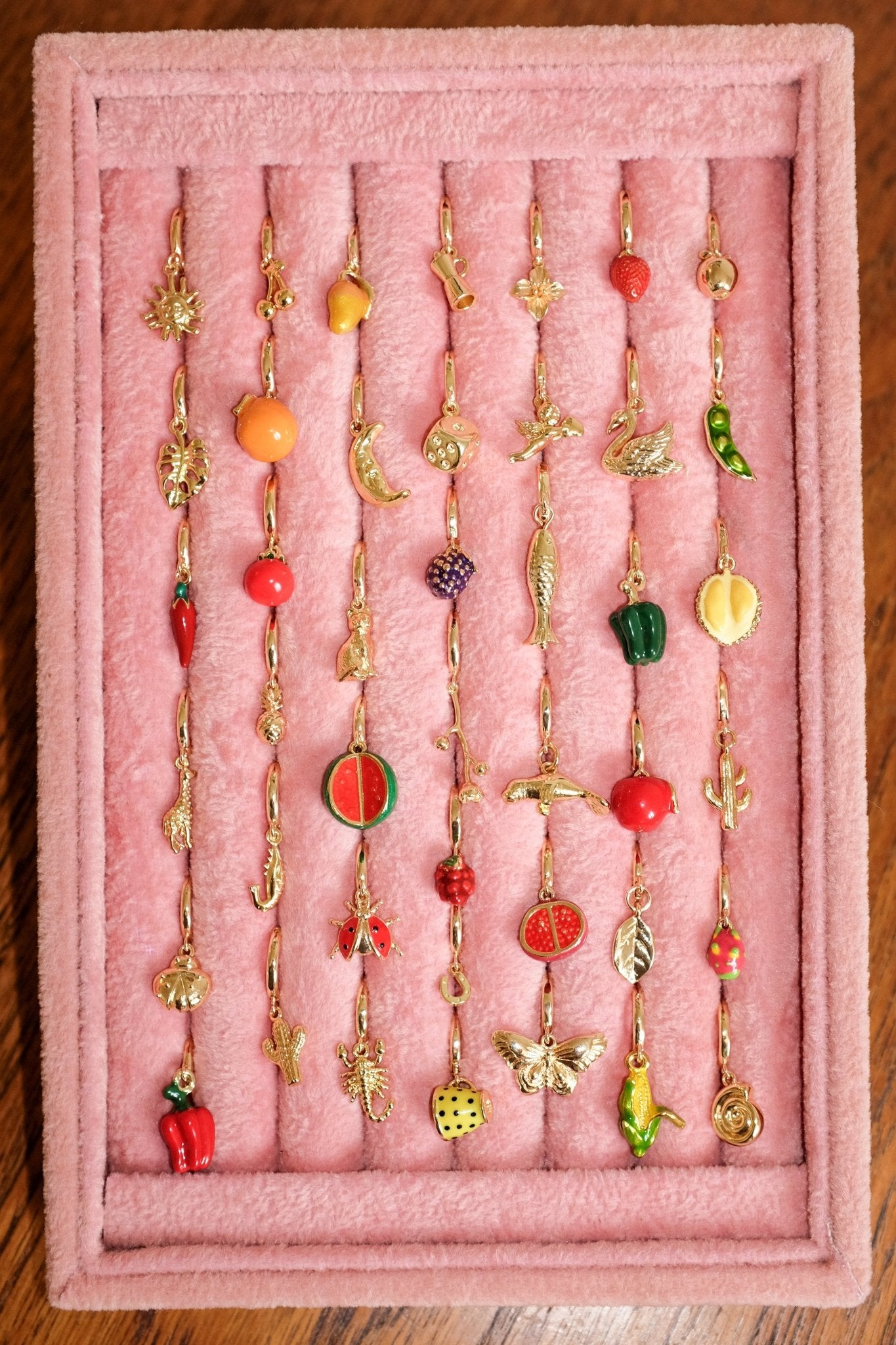 Collection of colorful earrings on a pink display stand.