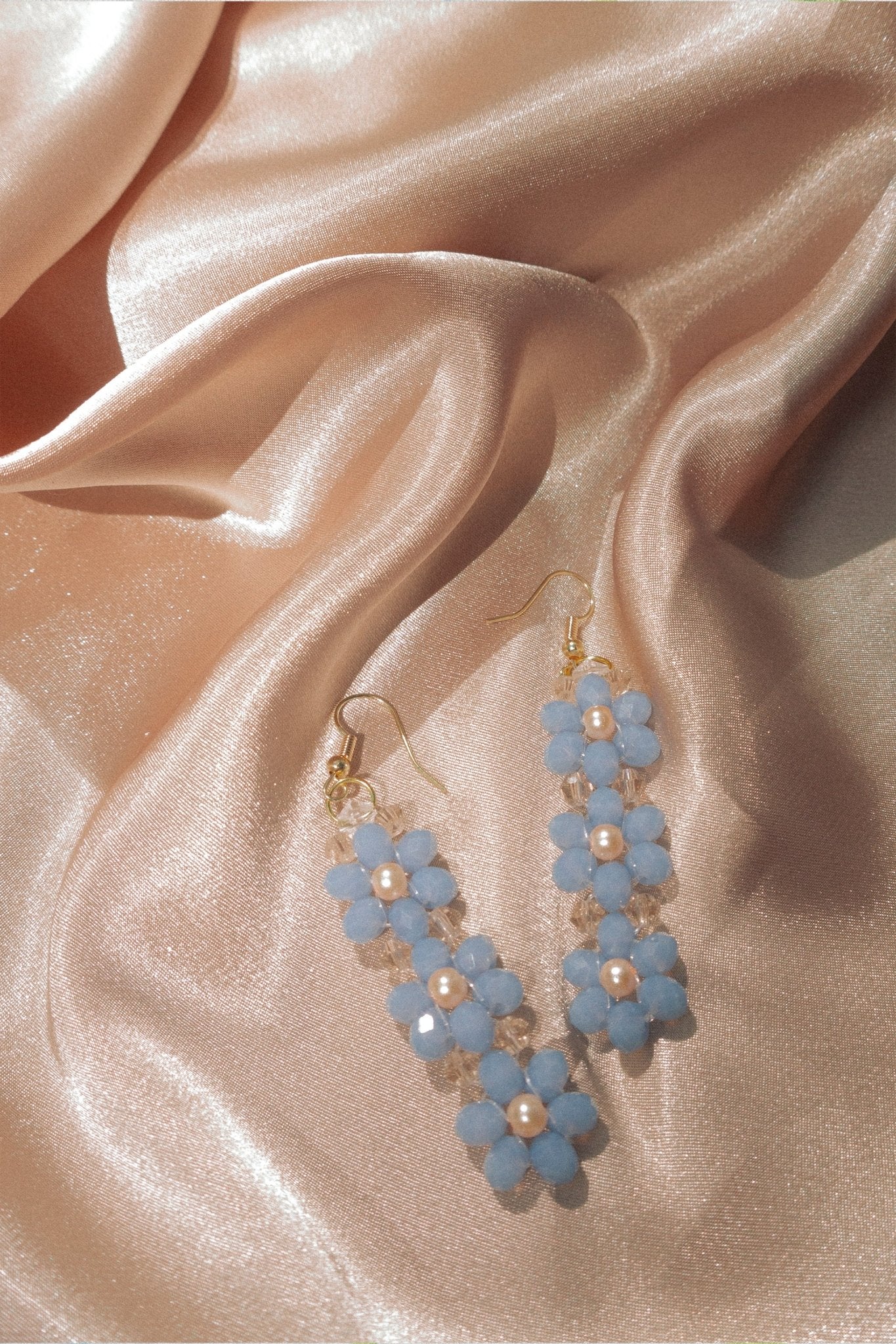Flatlay of Jennifer Earrings on gold satin fabric.