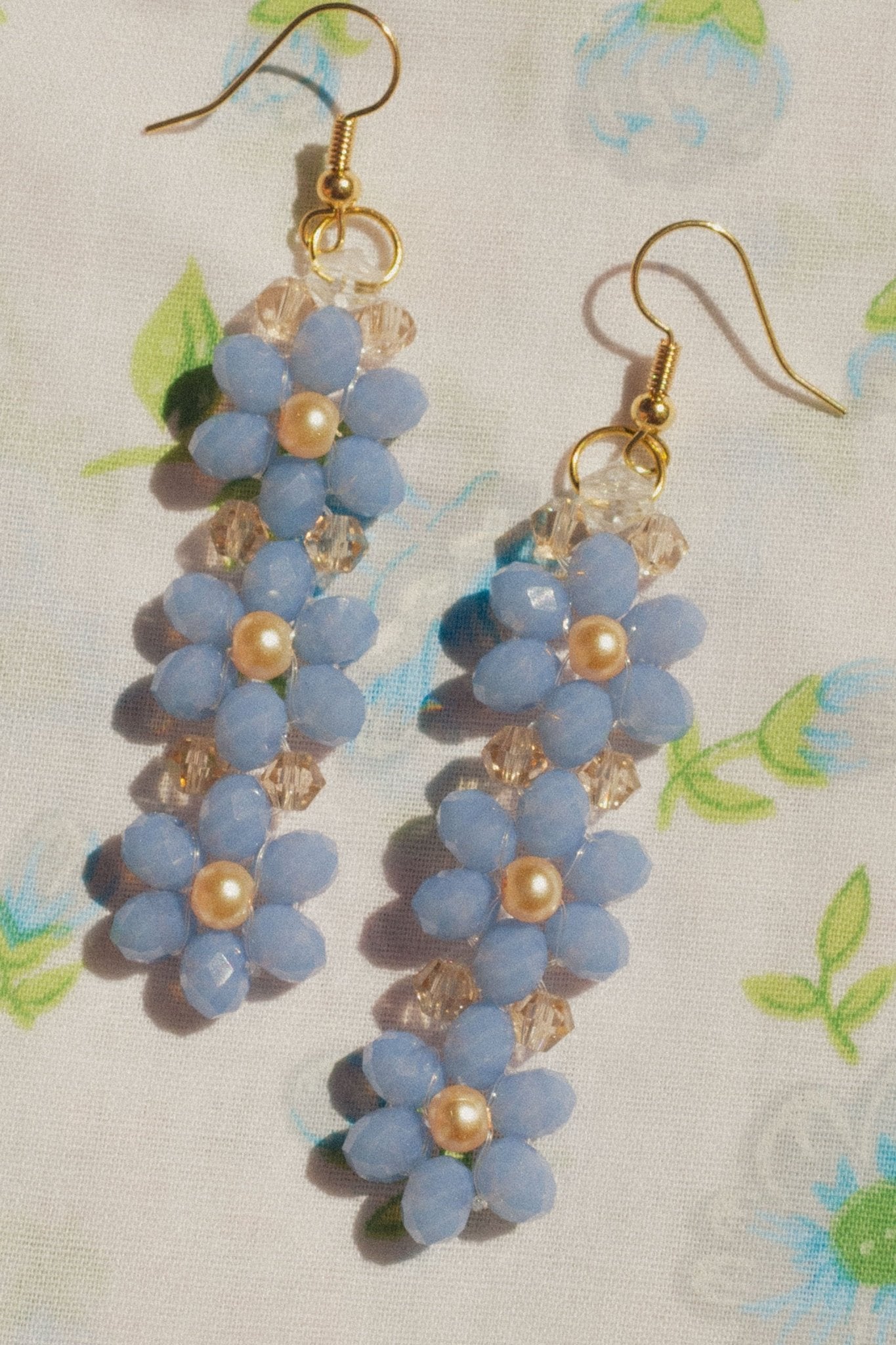 Handmade blue beaded flower earrings displayed against neutral background.